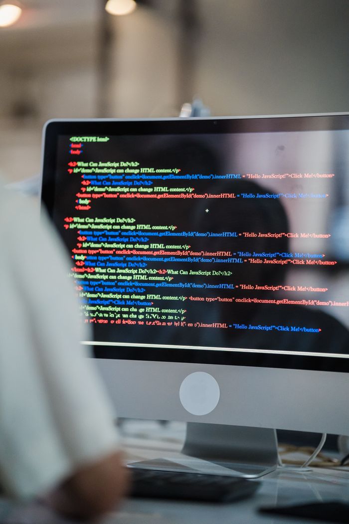Waarom 24/7 websitebewaking belangrijk is voor uw bedrijf A close-up of a computer screen displaying colorful coding script in an office environment.